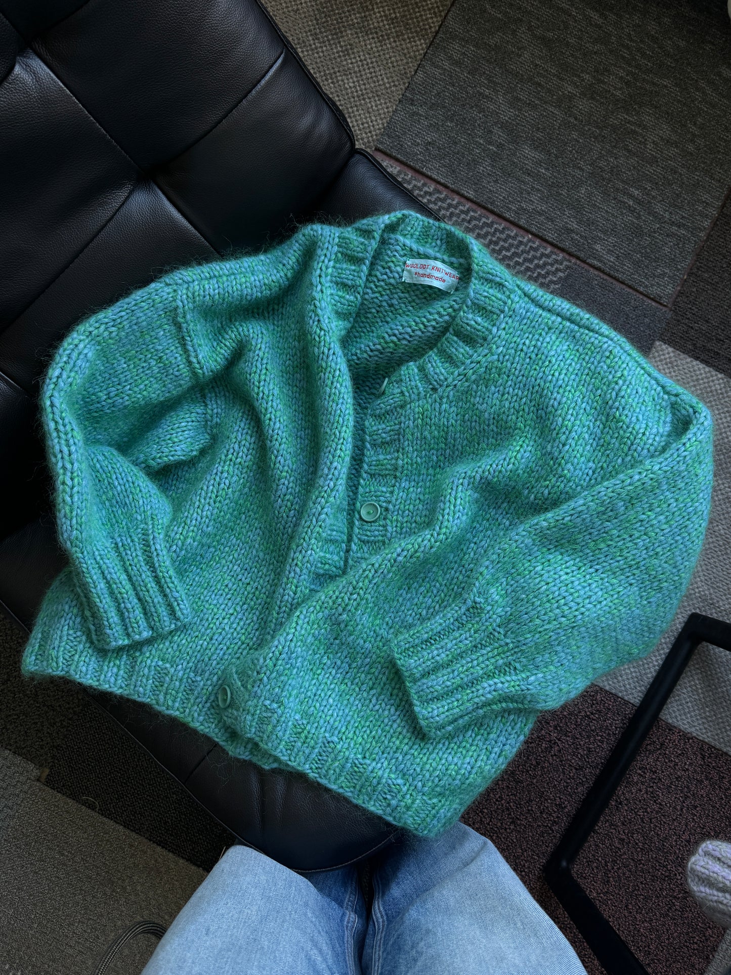 Green knitted sweater on a black leather chair