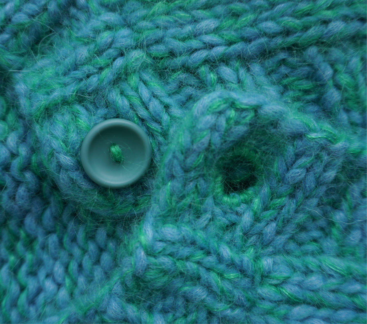 Close-up of green and blue knitted fabric with a button