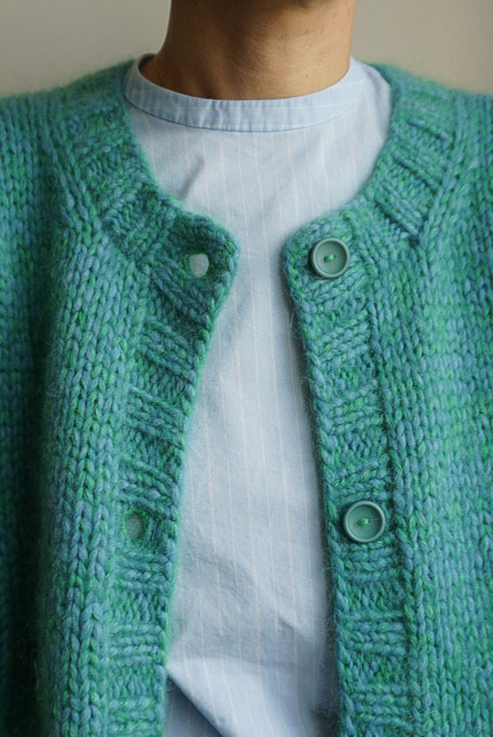 Green knitted cardigan with buttons on a neutral background