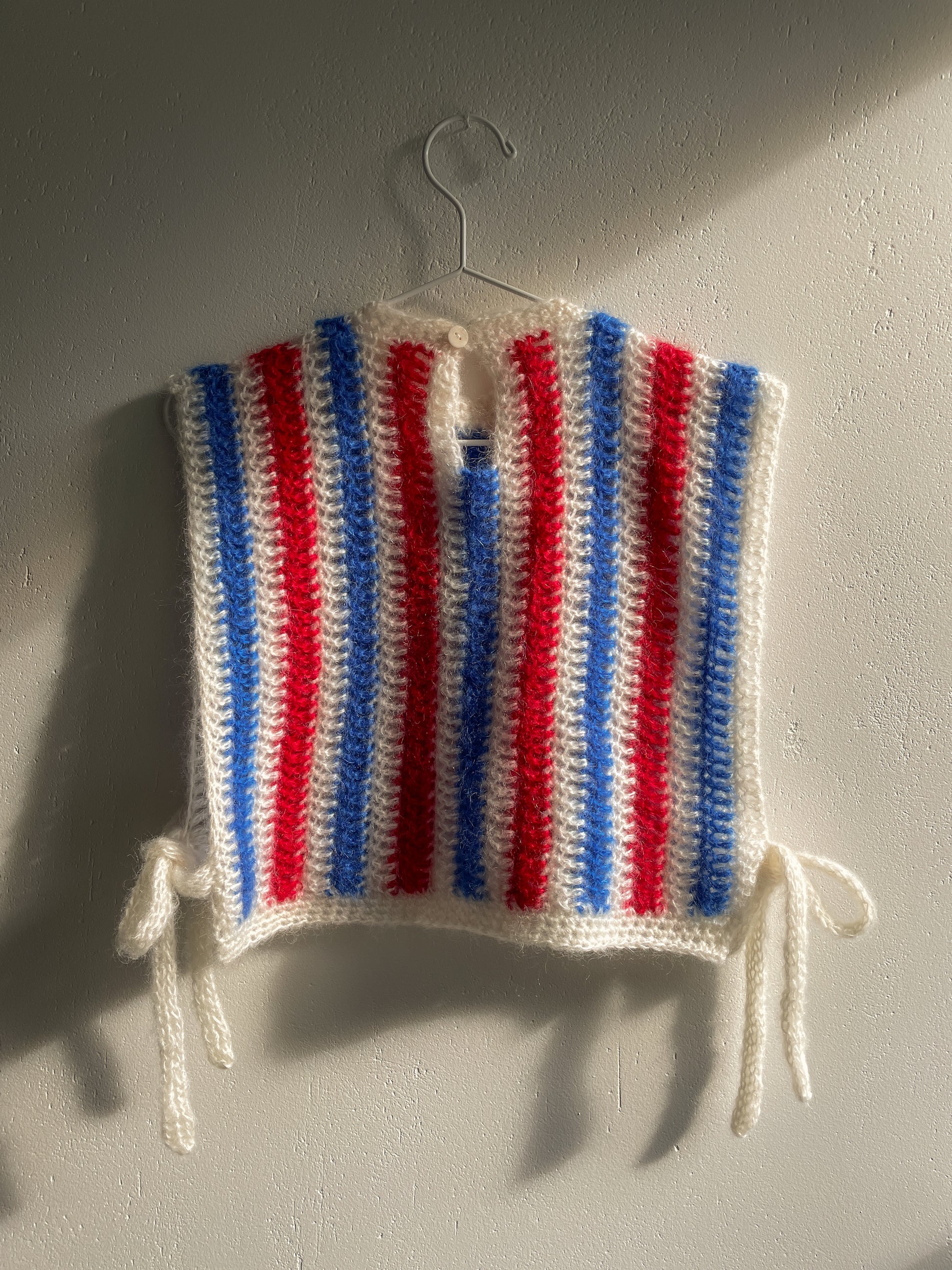 white red blue crochet mohair vest in vertical thin stripes. at the back vest is buttoned with small white button near the neck.