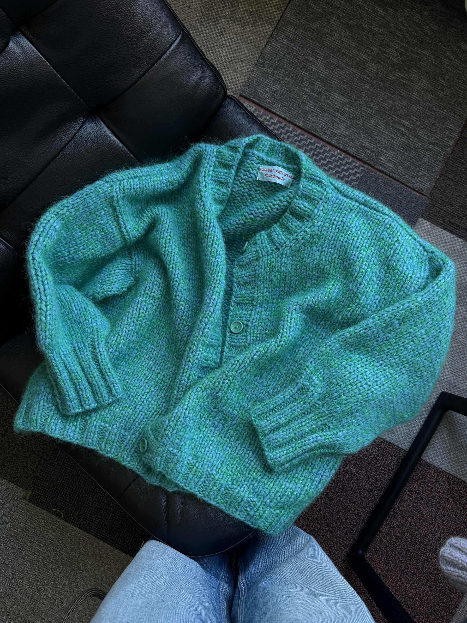 Green knitted sweater on a black leather chair