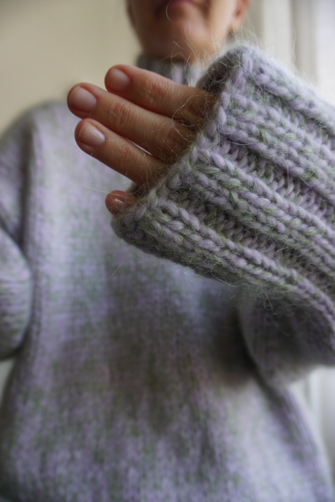 Close-up of a hand wearing a textured light purple knit cuff.