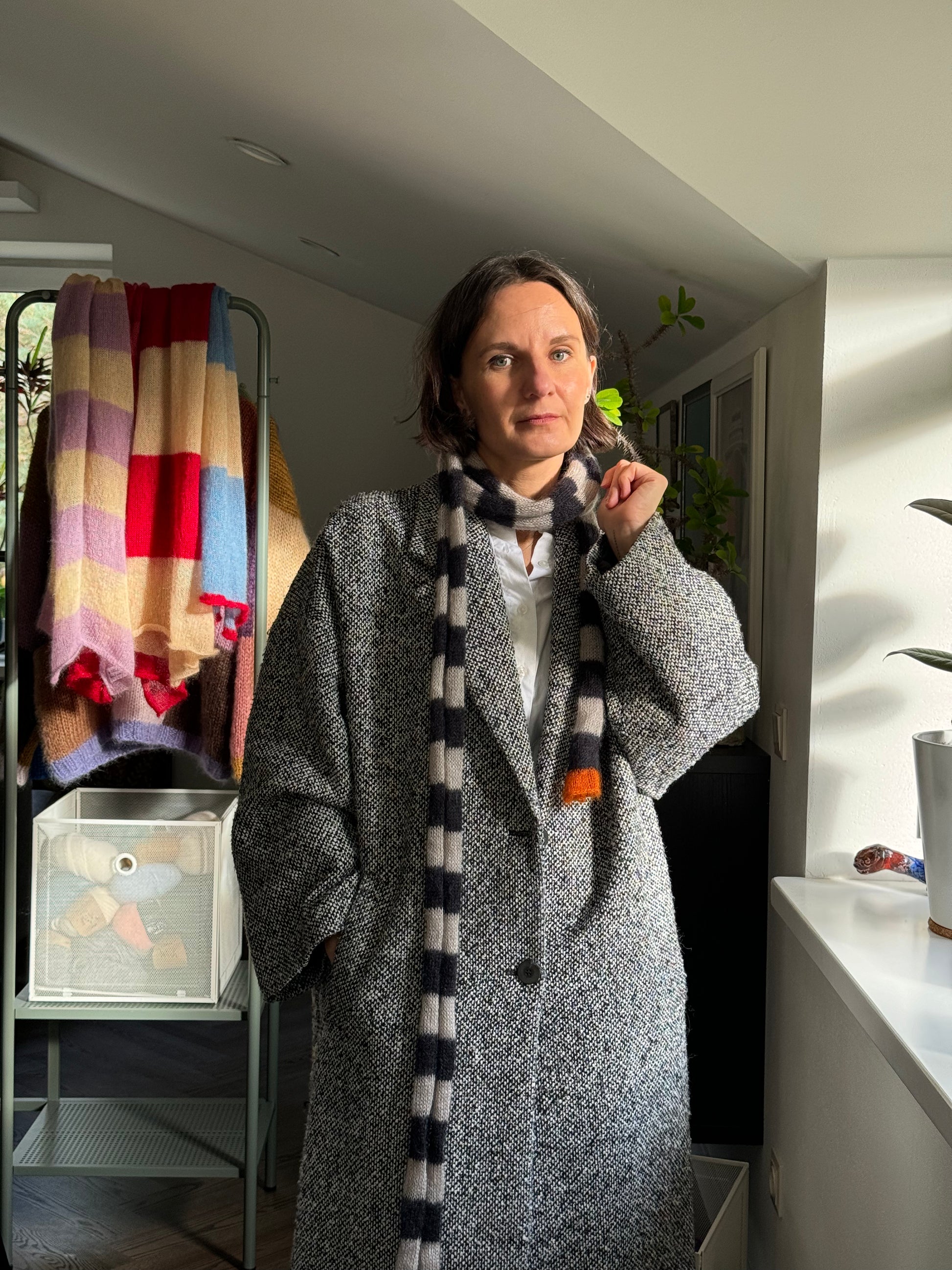 woman wearing coat and long thin skinny black and beige striped scarf