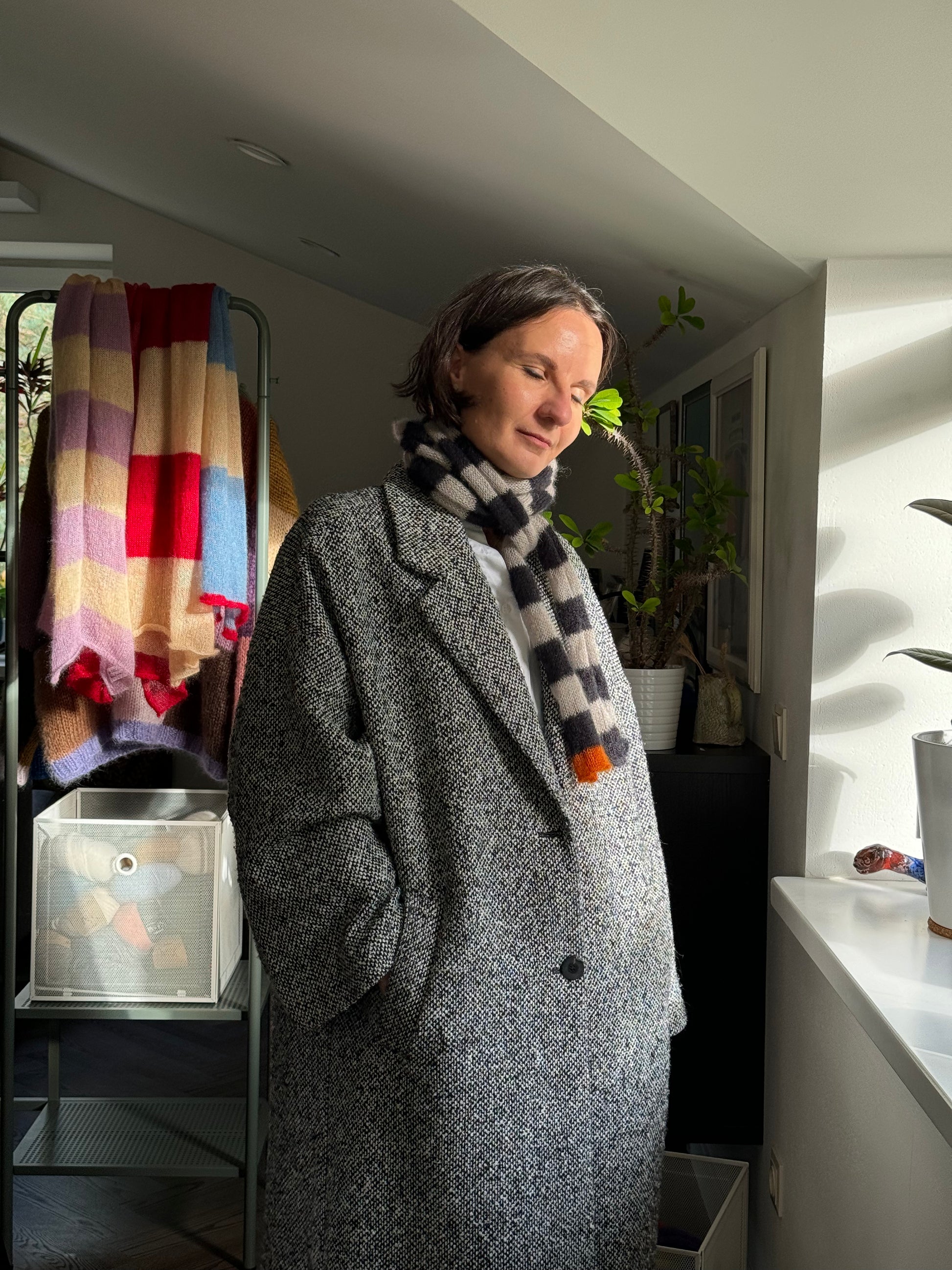woman wearing coat and long thin skinny black and beige striped scarf