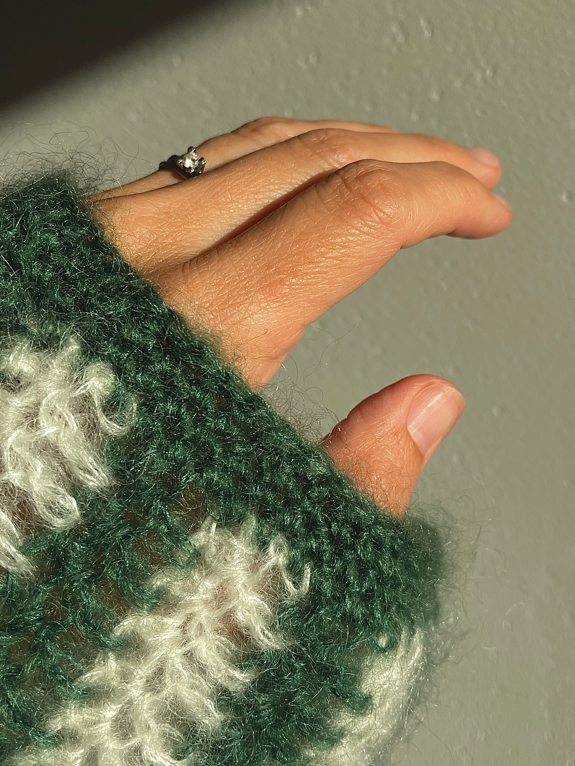 sleeve's fragment of handmade crocheted white and dark green mohair cardigan 